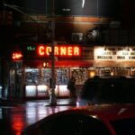 a red car driving down a street at night